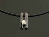 a silver necklace with a coin on it on a black surface