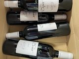 six bottles of wine in a cardboard box with labels on them