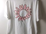 white t - shirt with a pink flower on it hanging on a hanger