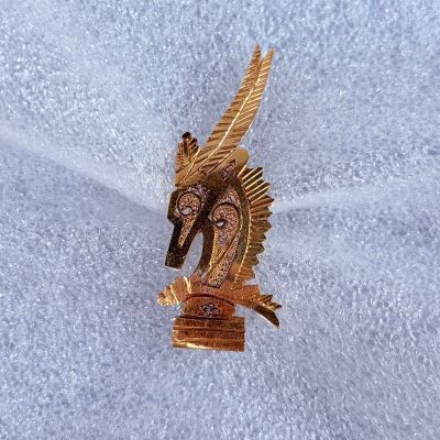 a gold horse brooch on a white cloth