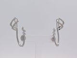 une paire de boucles d'oreilles créoles en diamant posées sur un présentoir transparent