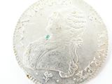 an image of a silver coin with a green stone in the center