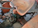 a rusted tractor sitting in a garage next to other vehicles