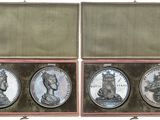 three silver coins in a wooden case with a white background