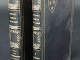 two old books are sitting side by side on a black surface