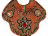 an orange beaded necklace with a red stone in the center