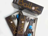 trois livres posés sur une table blanche, avec une voiture bleue devant