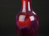 a red vase sitting on a black surface