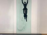 une sculpture en verre représentant un homme sur une planche de surf, posée sur une table