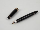 deux stylos à plume noirs et dorés posés sur une table blanche