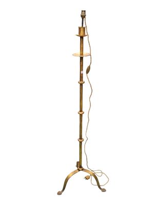a brass floor lamp with a glass shade on top of it