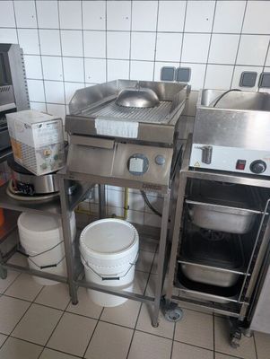 a kitchen with a stove, sink, and buckets on the floor