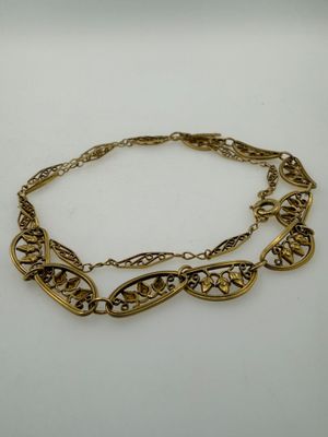 a close up of a gold chain bracelet on a white surface