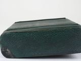 an old book with a green cover sitting on top of a white surface