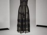 une robe noire posée sur un mannequin dans une pièce blanche