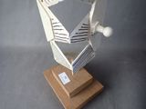 a paper sculpture of a bird on a wooden stand