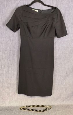 une robe noire suspendue à un cintre à côté d'une ceinture noire