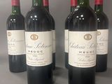 quatre bouteilles de vin rouge sont alignées sur une table