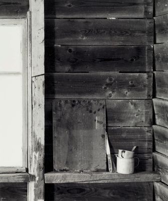 black and white photograph of a window and shelf in an old wooden cabin