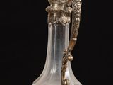 a glass vase with a silver handle on a wooden table