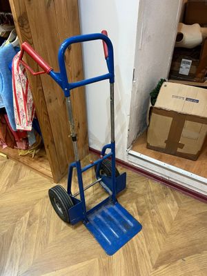 un diable bleu posé par terre à côté d'un carton