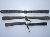 several knives are laying on a white surface with a clock in the background