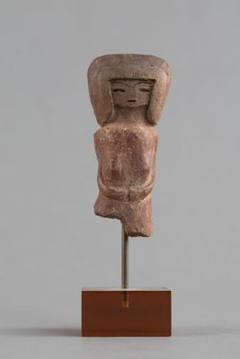 une statue ancienne représentant un homme, dont la tête repose sur un socle en bois