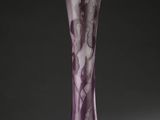 un vase en verre violet posé sur une table blanche près d'un mur noir
