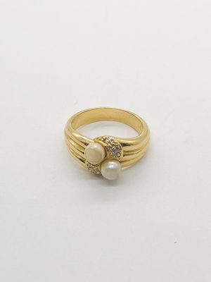 a close up of a gold ring with two pearls on it