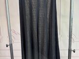 black skirt hanging on a rack in a room with white walls