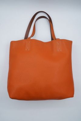 un sac fourre-tout en cuir orange sur fond blanc