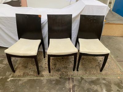 trois chaises noires et blanches placées les unes à côté des autres devant un canapé blanc