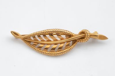 un gros plan d'une broche en feuille d'or sur fond blanc