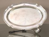 un plateau en argent avec une cuillère et un repose-cuillère posés sur une table