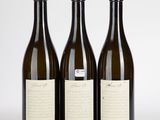 trois bouteilles de vin posées les unes à côté des autres sur une surface blanche