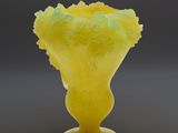 a yellow vase with a green flower inside of it