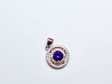 un gros plan d'un pendentif en forme de diamant violet et blanc posé sur une surface blanche