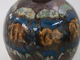 a brown and blue vase sitting on a white surface