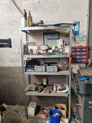 une étagère avec des outils et une poubelle dans un garage