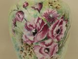 a vase with flowers painted on it sitting on a table