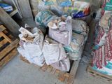de nombreux sacs de nourriture posés sur une palette, à côté de palettes de bois