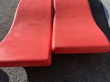 two red plastic benches sitting on top of a parking lot