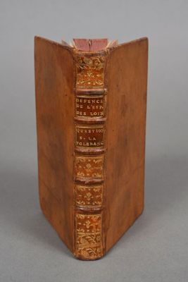 an old book is sitting on a table with a gray background