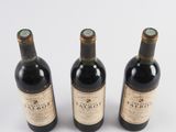 three bottles of wine are lined up on a white surface