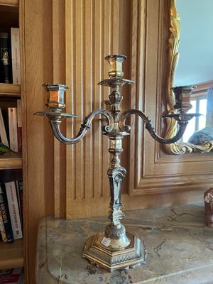 un candélabre en argent avec deux bougies, posé sur une table en marbre