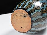 a close up of a blue and brown vase on a white surface