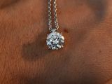 a person wearing a necklace with a diamond on it