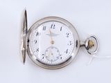 une vieille montre de poche à laquelle est accrochée une chaîne sur le côté