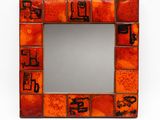 orange and brown mosaic mirror with black writing on it