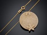 un collier en or avec un pendentif circulaire et une chaîne, sur fond noir